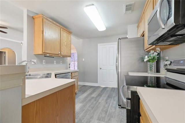 kitchen with visible vents, arched walkways, a sink, light wood-style floors, and stainless steel appliances
