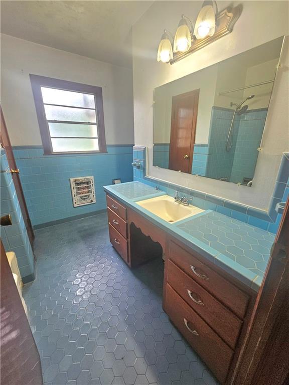 813 2nd Ave, Harvey, LA 70058 - bathroom featuring heating unit, tile walls, wainscoting, and a shower