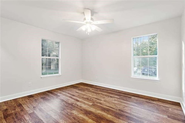 spare room featuring baseboards, dark wood-style flooring, and ceiling fan
