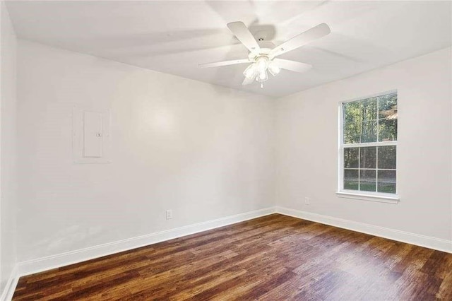 spare room featuring baseboards, a ceiling fan, electric panel, and dark wood-style floors