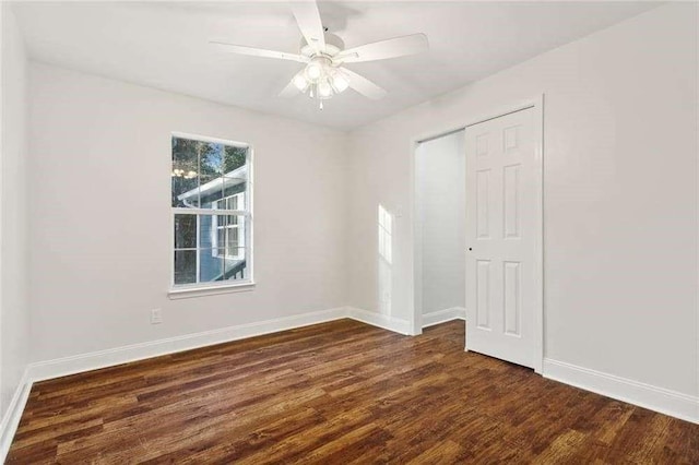empty room featuring baseboards, ceiling fan, and dark wood-style floors