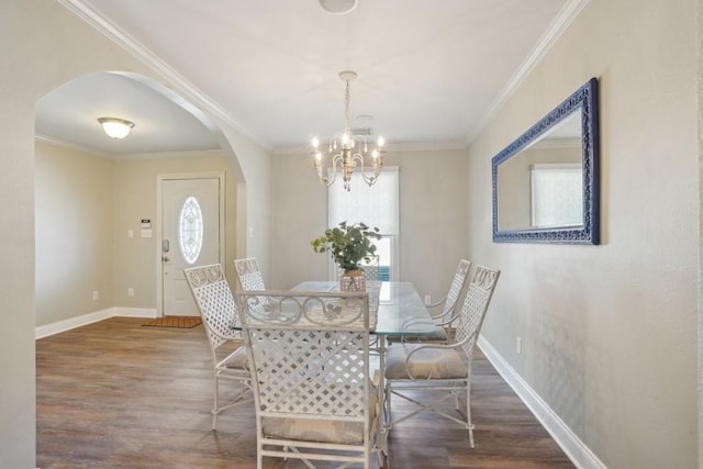 dining space with an inviting chandelier, arched walkways, baseboards, wood finished floors, and ornamental molding