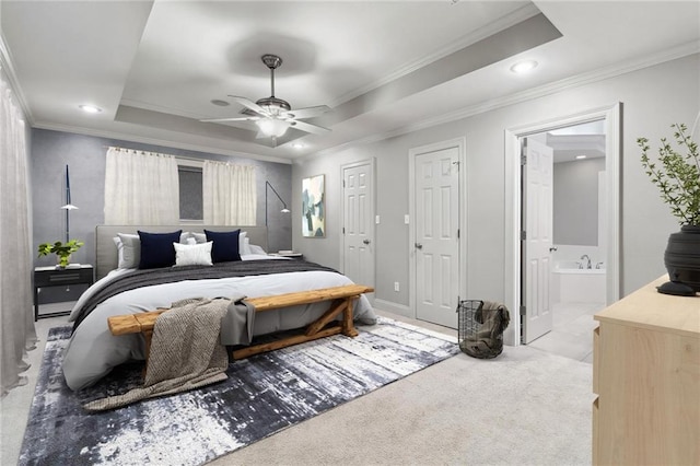 carpeted bedroom featuring ornamental molding, a raised ceiling, and ensuite bath