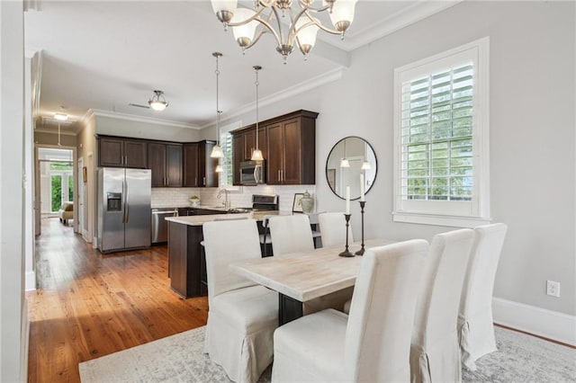 dining area with a healthy amount of sunlight, ornamental molding, light wood-style flooring, and a chandelier