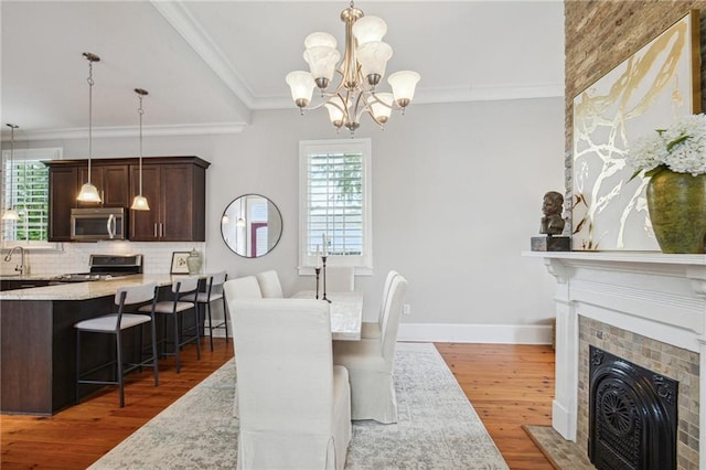 dining room with ornamental molding, a chandelier, wood finished floors, and a healthy amount of sunlight