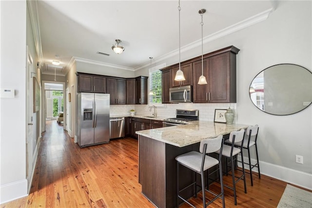 kitchen with visible vents, a peninsula, dark brown cabinetry, a sink, and appliances with stainless steel finishes
