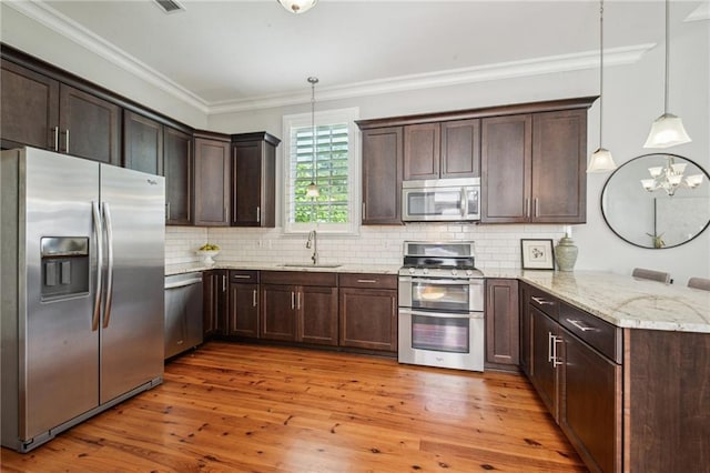 kitchen featuring dark brown cabinetry, appliances with stainless steel finishes, a sink, a peninsula, and ornamental molding