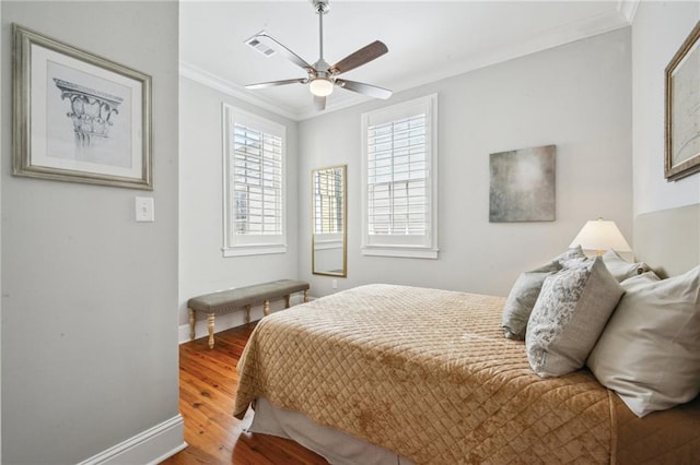 bedroom with visible vents, ornamental molding, wood finished floors, baseboards, and ceiling fan