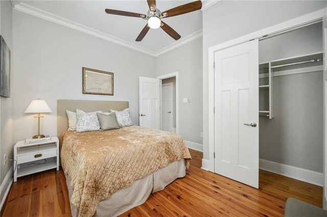 bedroom featuring a closet, ornamental molding, wood finished floors, baseboards, and ceiling fan