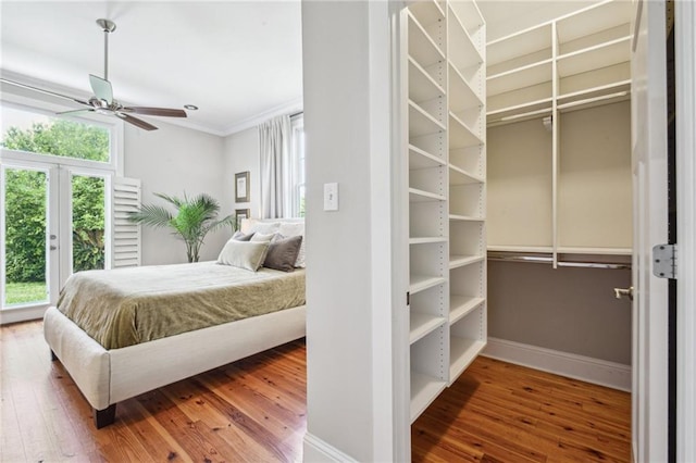 bedroom featuring baseboards, crown molding, hardwood / wood-style flooring, and ceiling fan