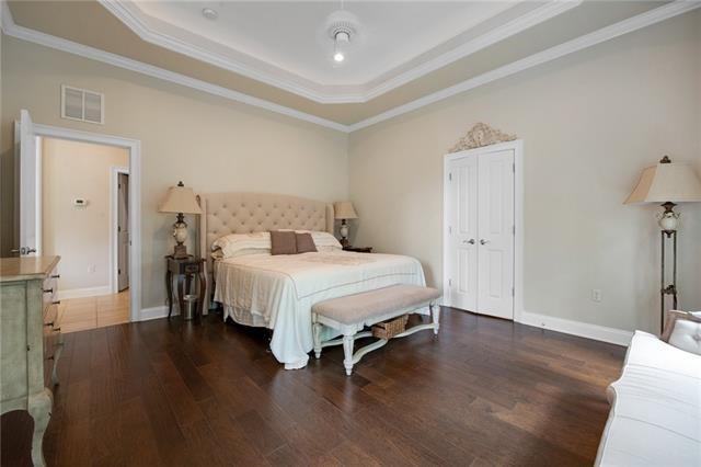 bedroom featuring crown molding, a tray ceiling, wood finished floors, and visible vents