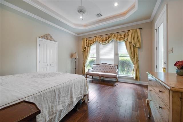 bedroom with dark wood-style flooring, baseboards, a tray ceiling, visible vents, and ornamental molding