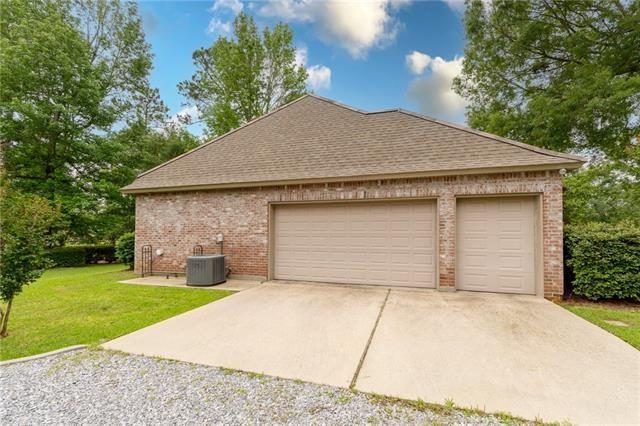 view of property exterior with driveway, a lawn, central air condition unit, brick siding, and a shingled roof