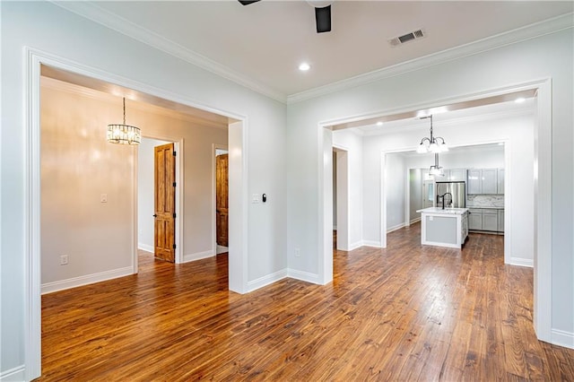 unfurnished living room featuring visible vents, ornamental molding, dark wood-style flooring, baseboards, and ceiling fan with notable chandelier