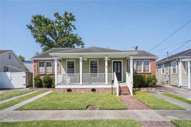 view of front of home featuring fence, covered porch, a front yard, roof with shingles, and stucco siding