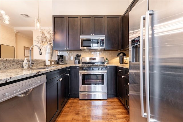 kitchen featuring visible vents, appliances with stainless steel finishes, a sink, ornamental molding, and light wood-style flooring
