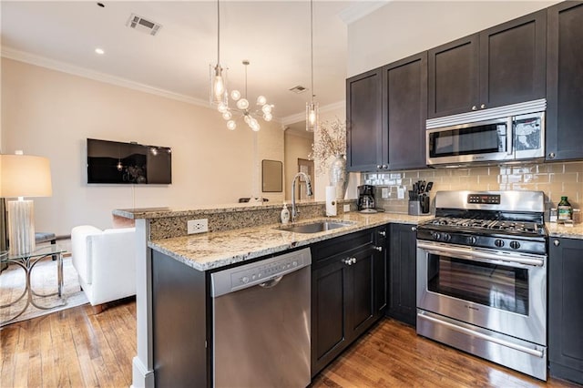kitchen featuring visible vents, wood-type flooring, crown molding, a sink, and stainless steel appliances