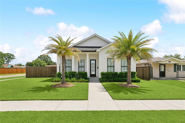 bungalow-style home featuring a front lawn and fence