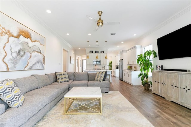 living room featuring crown molding, recessed lighting, ceiling fan, and wood finished floors