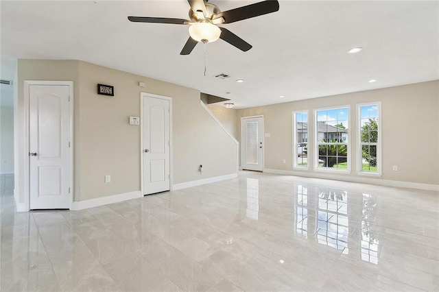 unfurnished living room featuring a ceiling fan, baseboards, visible vents, and marble finish floor