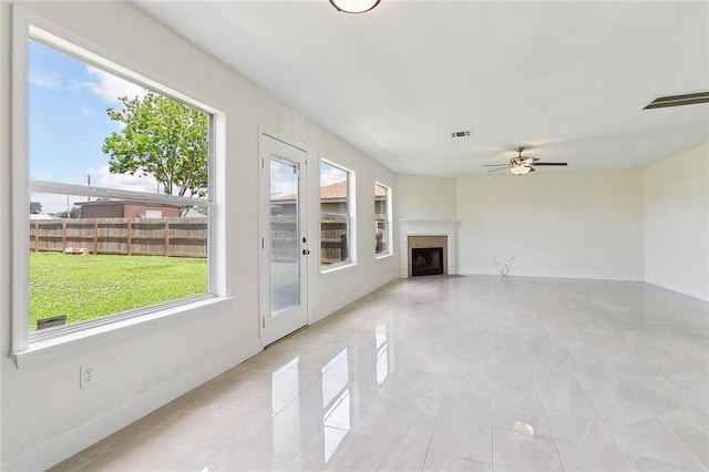 unfurnished living room with a ceiling fan, visible vents, a fireplace, light tile patterned floors, and baseboards