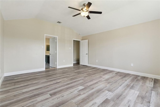 interior space with connected bathroom, baseboards, wood finished floors, lofted ceiling, and visible vents