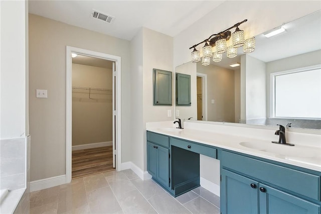 bathroom featuring double vanity, visible vents, a sink, and a spacious closet