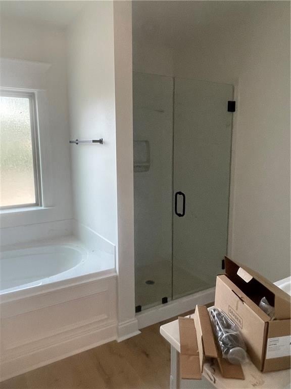 full bath featuring a shower stall, a bath, and wood finished floors