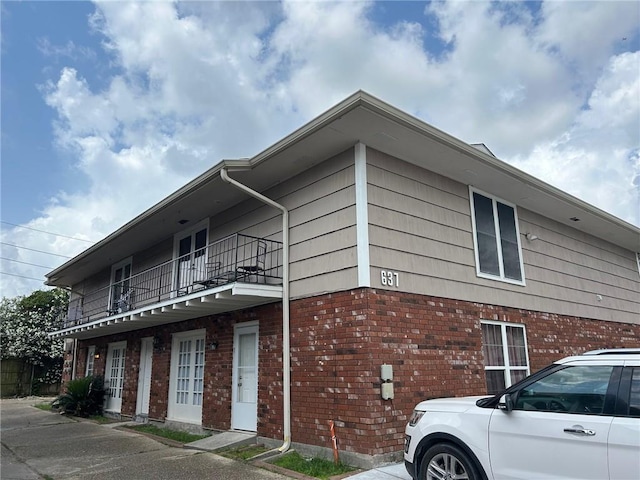 view of side of home with brick siding and a balcony