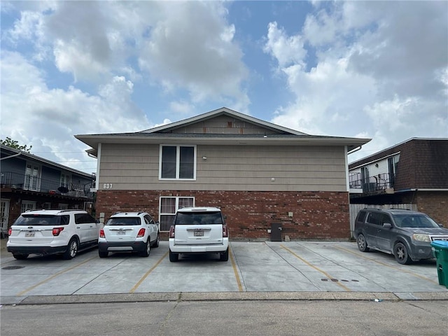 view of front of house with uncovered parking and brick siding