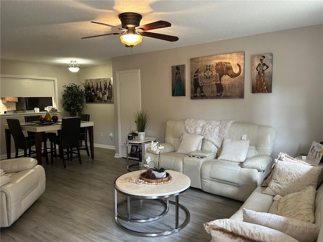 living room with a ceiling fan, baseboards, and wood finished floors