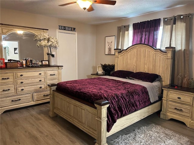 bedroom with dark wood-style flooring, a ceiling fan, and a textured ceiling