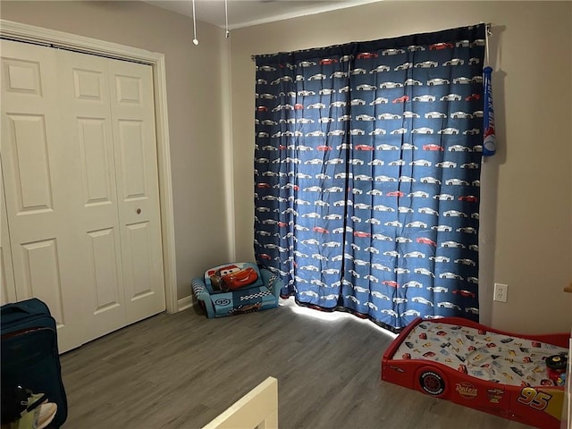 bedroom with baseboards, wood finished floors, and a closet