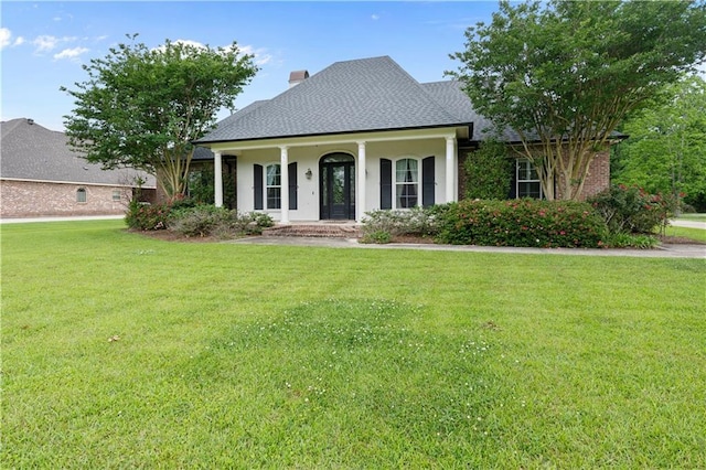 view of front of house featuring a porch, a shingled roof, a front lawn, and a chimney