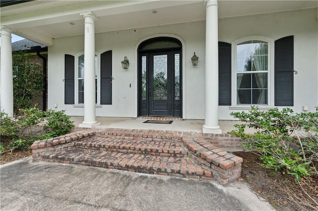 entrance to property featuring stucco siding and covered porch