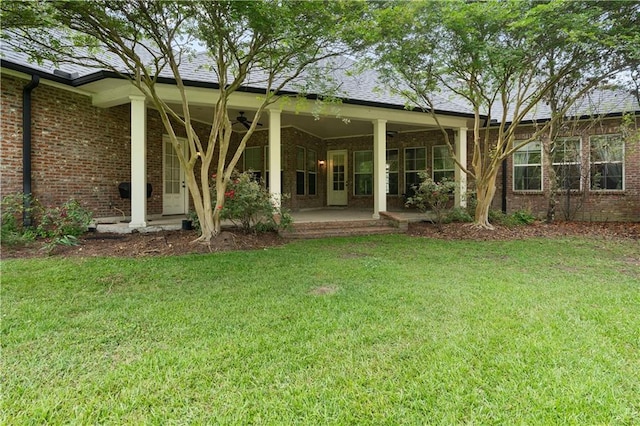 back of house featuring brick siding, ceiling fan, and a yard