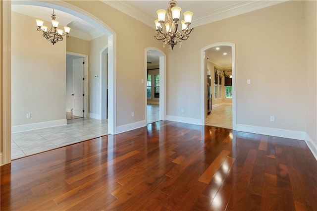 unfurnished room featuring crown molding, arched walkways, wood finished floors, and a chandelier