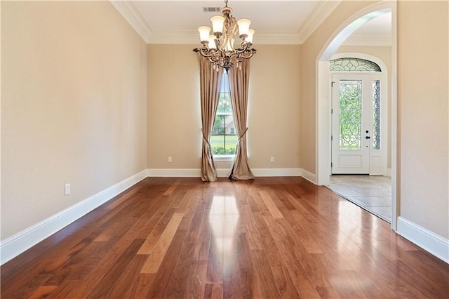 foyer entrance with crown molding, arched walkways, an inviting chandelier, and wood finished floors