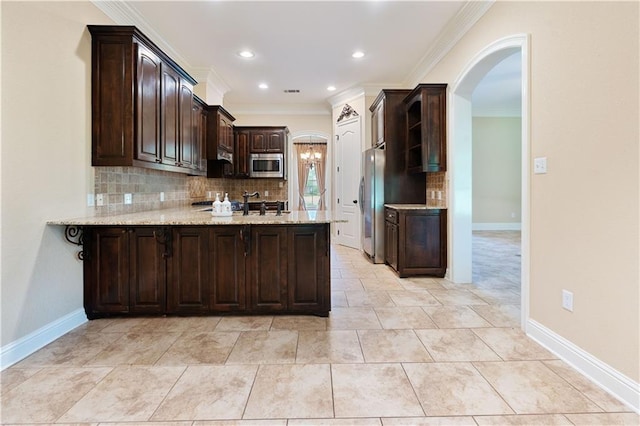 kitchen with appliances with stainless steel finishes, arched walkways, dark brown cabinets, a peninsula, and ornamental molding