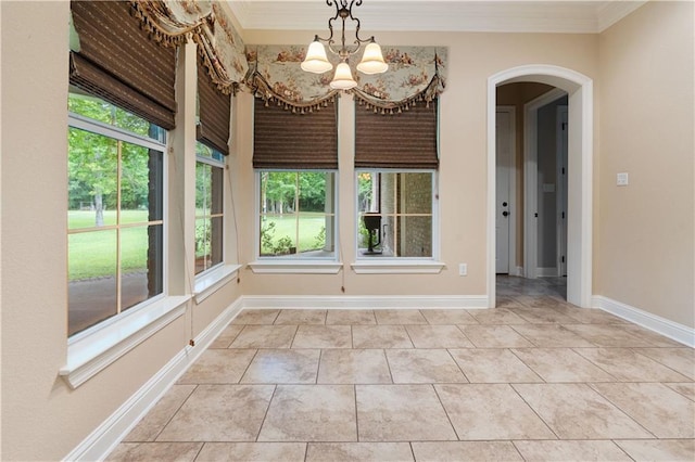 unfurnished dining area featuring plenty of natural light, arched walkways, a notable chandelier, and ornamental molding