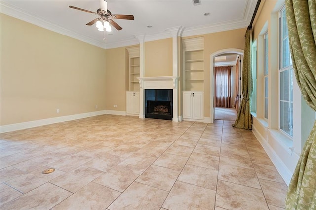 unfurnished living room featuring crown molding, arched walkways, a ceiling fan, and built in shelves