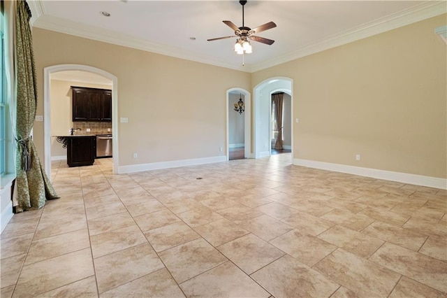 spare room featuring arched walkways, ornamental molding, baseboards, and a ceiling fan