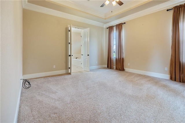 carpeted empty room featuring a raised ceiling, ornamental molding, baseboards, and a ceiling fan