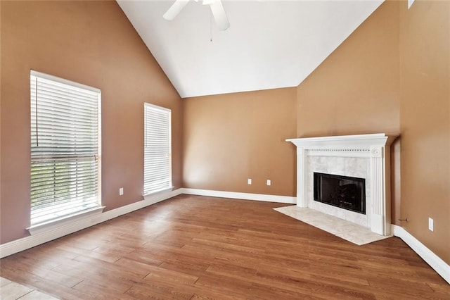 unfurnished living room with ceiling fan, wood finished floors, and a tile fireplace