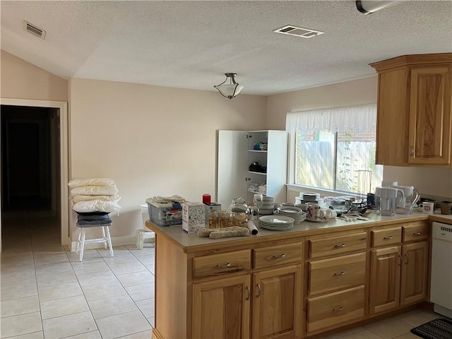 kitchen featuring light tile patterned floors, light countertops, white dishwasher, and visible vents