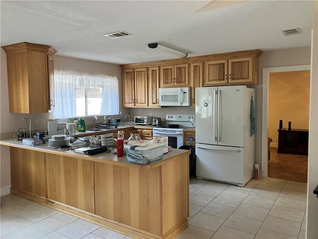 kitchen with a sink, white appliances, a peninsula, light tile patterned floors, and visible vents