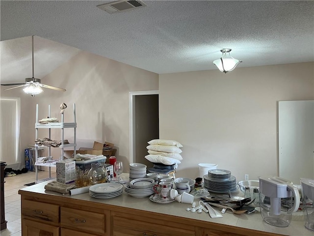 kitchen with light tile patterned floors, light countertops, a textured ceiling, and visible vents