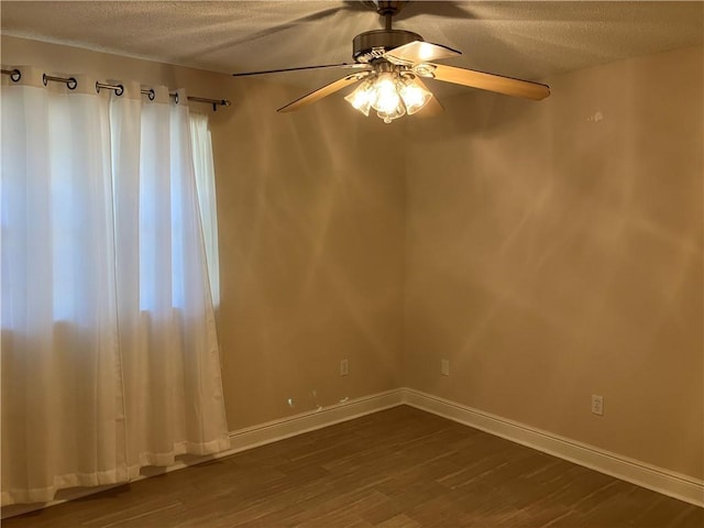 unfurnished room featuring a ceiling fan, a textured ceiling, dark wood finished floors, and baseboards