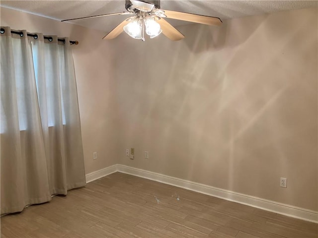 unfurnished room with baseboards, ceiling fan, a textured ceiling, and wood finished floors