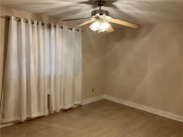 empty room featuring baseboards, ceiling fan, and wood finished floors